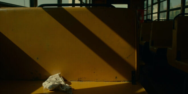 Empty yellow school bus interior with a crumpled piece of paper on a seat, dramatic lighting and emergency colors