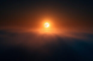 Large full moon glowing orange-amber near horizon against dark indigo night sky with atmospheric gradient