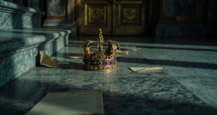 Ornate golden crown lying on marble palace steps with closed doors in background