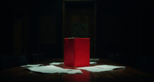 Red briefing folder on dark wooden conference table in empty meeting room with scattered papers and chairs