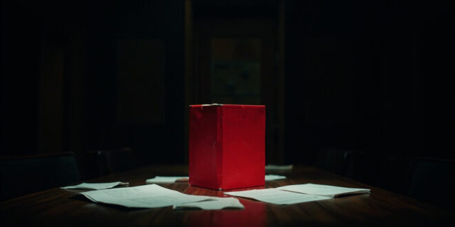 Red briefing folder on dark wooden conference table in empty meeting room with scattered papers and chairs