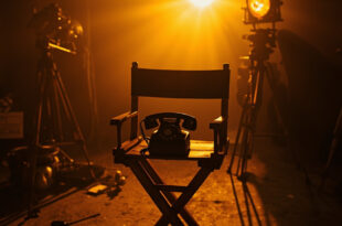 Vintage rotary telephone on wooden director's chair under dramatic studio lighting on empty film set