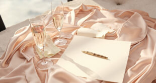 Wedding preparation items including silk robes, champagne flutes, and decorations arranged on hotel suite furniture with ocean view