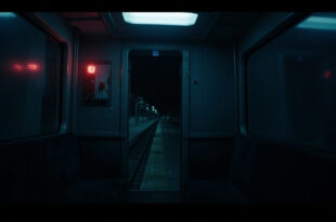 Empty train carriage interior with illuminated emergency button and fluorescent lighting casting stark shadows
