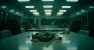 Empty school cafeteria with single lunch box on table under harsh fluorescent lights
