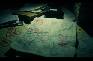 Topographic military maps with classification markings spread across a tactical command table in low light