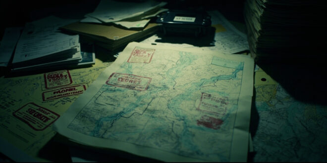 Topographic military maps with classification markings spread across a tactical command table in low light