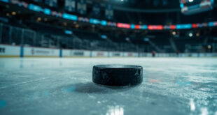 Hockey puck on ice surface in empty championship arena with dramatic lighting