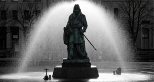 Bronze statue on stone base in city square being cleaned by high-pressure water equipment