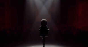 Professional microphone on stand in darkened television studio with dramatic stage lighting