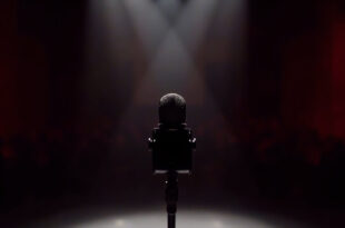 Professional microphone on stand in darkened television studio with dramatic stage lighting