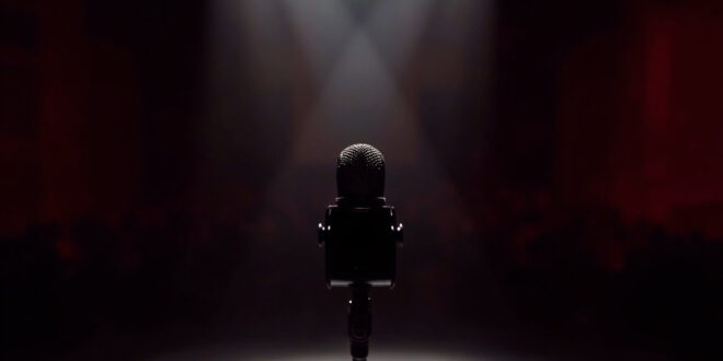 Professional microphone on stand in darkened television studio with dramatic stage lighting