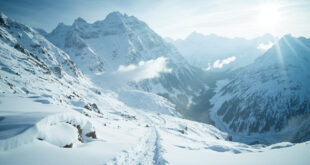 Snow-covered alpine mountain pass with thick white powder on peaks and valleys under overcast sky