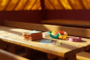 Colorful festival vouchers and admission wristbands scattered on wooden table in empty traditional German beer tent