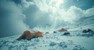 Camping tents and hiking equipment buried in deep snow on mountain slopes with swirling clouds overhead
