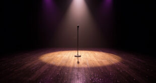 Lone microphone stand illuminated by spotlight on empty glittering dance floor in dark studio
