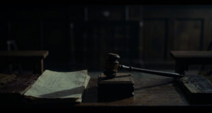 Wooden gavel and law books on dark courtroom bench in shadowy interior