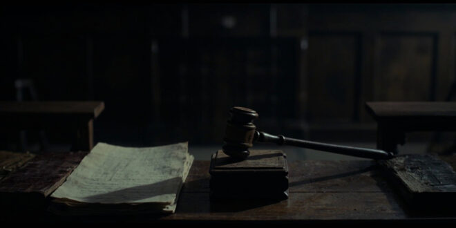 Wooden gavel and law books on dark courtroom bench in shadowy interior