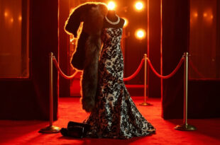 Black and white printed dress with faux-fur shawl, pearl necklace, and black clutch on red carpet backdrop