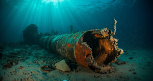 Broken underwater gas pipeline with torn metal edges lying on Baltic seabed surrounded by debris and sediment clouds