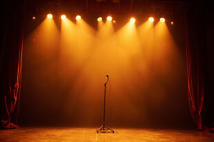 Empty concert stage with red velvet curtains opening, golden spotlights creating dramatic beams through darkness