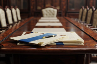 Formal diplomatic documents and ceremonial pen on polished conference table in empty meeting room