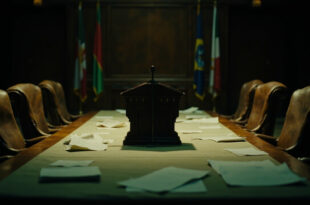 Empty diplomatic conference room with formal table, microphones, and international flags in background