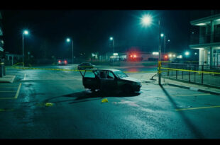 Police tape surrounds empty parking lot near daycare building with evidence markers on asphalt