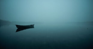 Empty fishing kayak floating on misty lake water during early morning hours