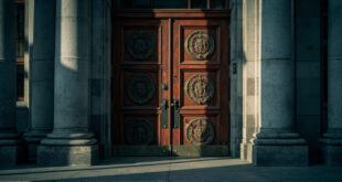Closed heavy wooden courthouse doors with official seals and security locks in gray stone building