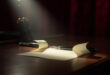 Cream paper note rests on polished wooden desk beside fountain pen in dramatic spotlight