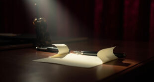 Cream paper note rests on polished wooden desk beside fountain pen in dramatic spotlight