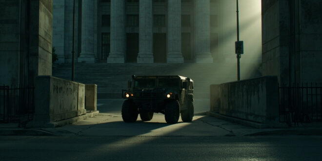 Military vehicle stationed outside concrete government building with security barriers on empty urban street