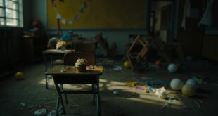 Empty classroom with scattered birthday decorations on wooden desk and overturned chairs