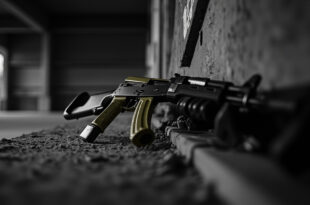 Military rifle and training equipment positioned on concrete ground in urban setting