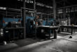Empty automotive factory floor with silent machinery and scattered safety equipment on workbenches