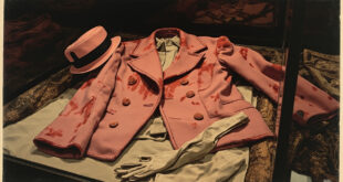 Pink wool suit jacket with dark stains preserved in climate-controlled archival storage