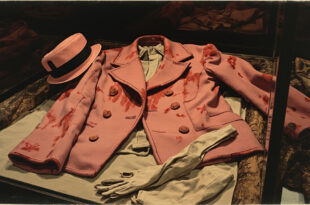 Pink wool suit jacket with dark stains preserved in climate-controlled archival storage
