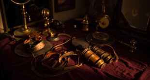 Vintage film reel, hot rollers, and microphone on velvet surface with warm theatrical lighting