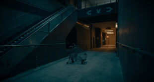 Empty shopping center escalator descending toward dim exit, abandoned cart near emergency door, cold blue lighting