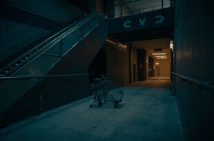 Empty shopping center escalator descending toward dim exit, abandoned cart near emergency door, cold blue lighting